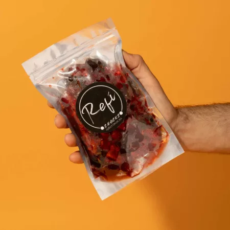 Hand holding a bag of Gummy bears coated with RefiSnacks coated with chamoy paste.