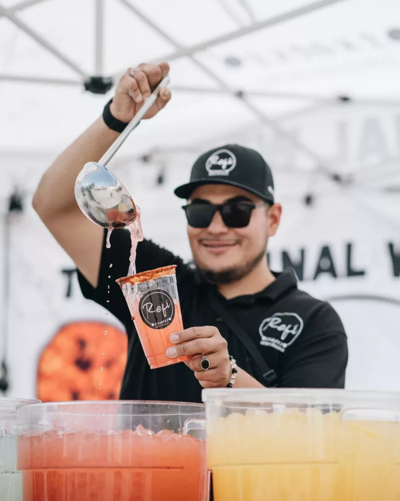 Refi pouring aguas frescas at an event.